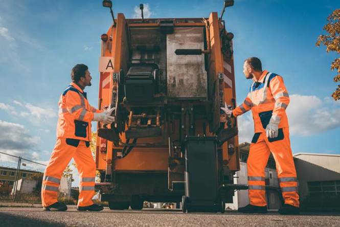 Men in orange uniforms standing next to a garbage truck

AI-generated content may be incorrect.